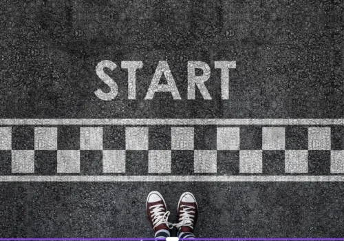 Faites le premier pas pour apprendre l’arabe – Lancez-vous aujourd’hui Vue aérienne de pieds s’apprêtant à franchir une ligne avec le mot « Tarte » écrit dessus, métaphore du premier pas vers l’apprentissage de l’arabe. Encouragez-vous à démarrer dès aujourd’hui et à progresser pas à pas.